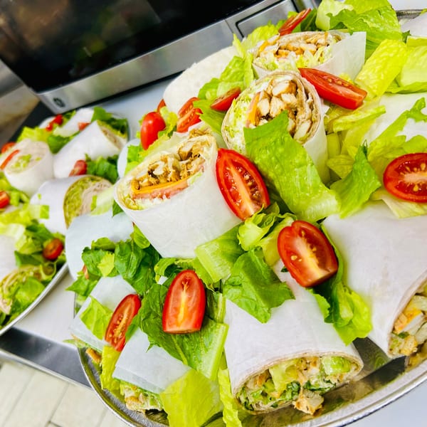 Platter of chicken wraps with lettuce and cherry tomatoes, ready to be served.